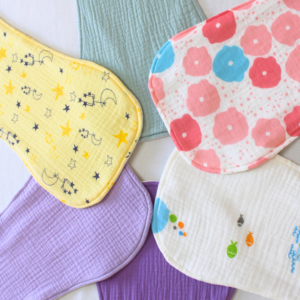 6 Different coloured handmade burp cloths placed in a circle. One side facing inwards.